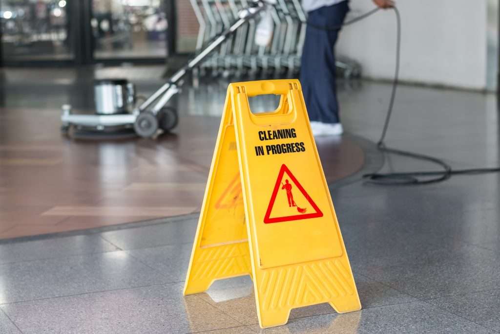 Woman polishing an office floors. She has put a cleaning in progress sign out