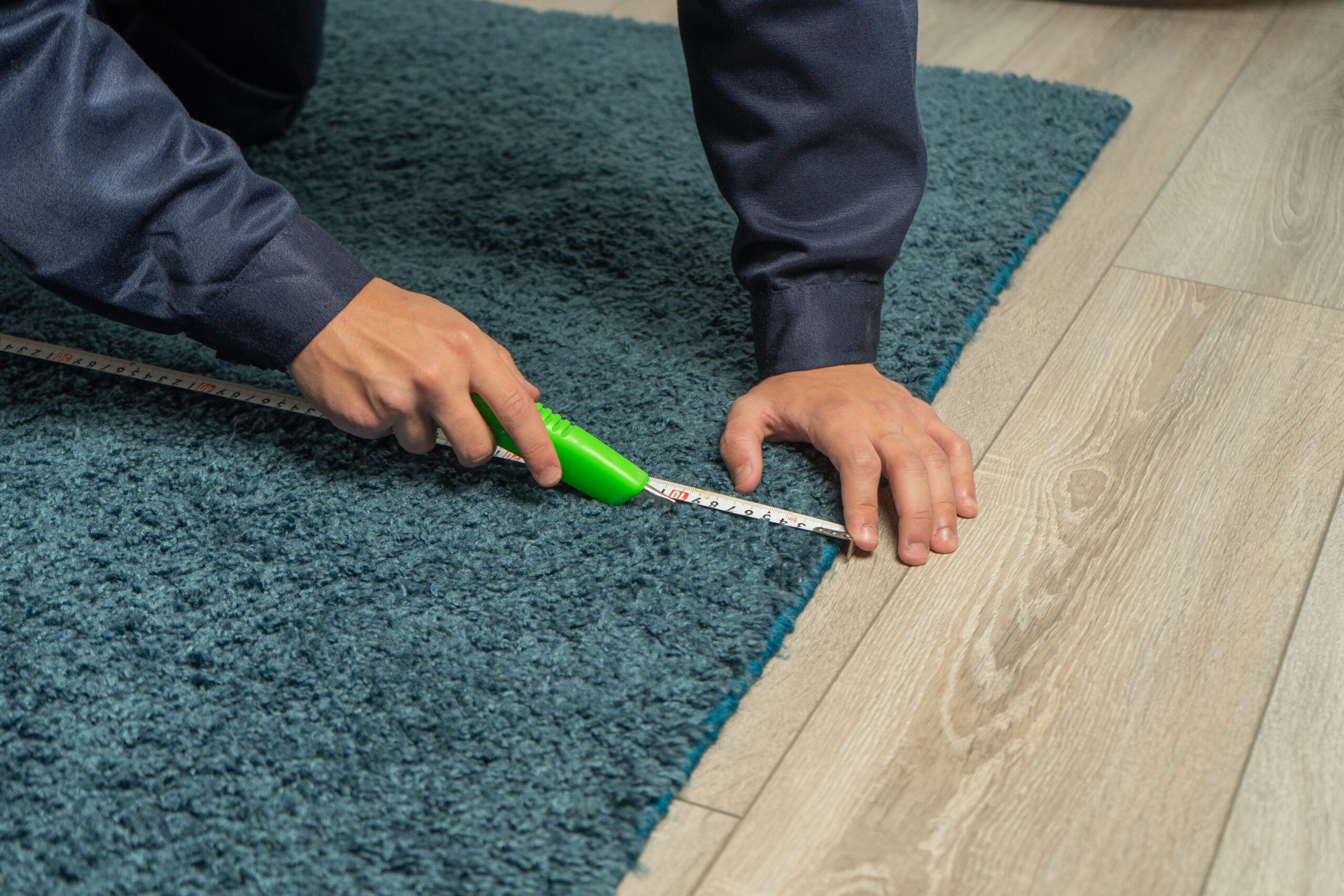 Worker using cutter while installing new carpet flooring in room. Carpet restoration, carpet trimming at home medical office cleaning